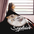 A woman is standing near a window, smiling and looking out. The image features a black blanket with a dog image and the name 